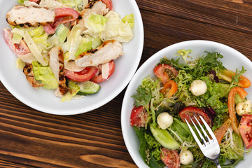 white deep plates with fresh salad ingredients mixed with sauce placed on an attractive background. A place for a menu, banner or advertisement