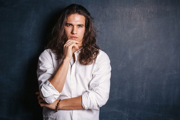 Handsome happy man in white shirt. Smiling guy with long hair on isolated background in studio....