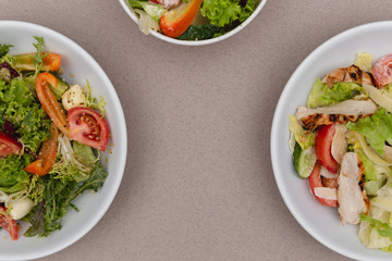 white deep plates with fresh salad ingredients mixed with sauce placed on an attractive background. A place for a menu, banner or advertisement