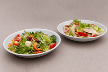 white deep plates with fresh salad ingredients mixed with sauce placed on an attractive background. A place for a menu, banner or advertisement