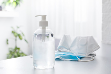 Face masks and hand sanitizer bottle on table for peple washing hands to help stop spreading outbreak coronavirus covid-19 for public health safety