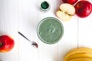 The concept of food and drink, diet and nutrition. Healthy green vegan smoothie with banana, spirulina and ripe apple for summer detoxification