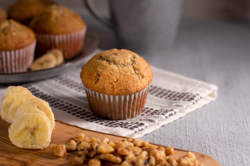 Homemade Banana Nut Muffins on Gray Linen with Fresh Sliced Bananas and Walnuts