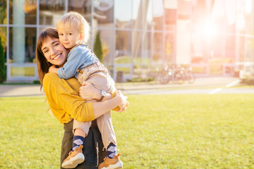 Fototapeta premium Happy young mother having fun with her kid - Son hugging his mum outdoor - Family connection, motherhood, love and tender moments concept - Focus on boy face