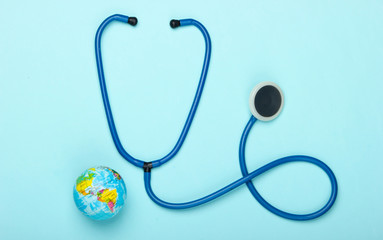 The problem of the global pandemic. Stethoscope and globe on a blue background. Global epidemic. Top view