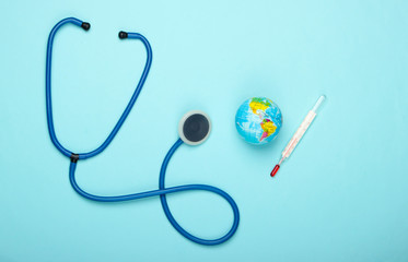 Global warming still life. Globe and thermometer, stethoscope on blue background. Global climate issues. Earth planet treatment. Eco concept