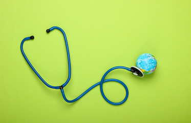 The problem of the global pandemic. Stethoscope and globe on green background. Global epidemic. Top view