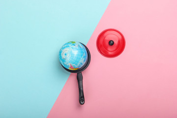 Global warming concept. Mini globe in a toy pan on a blue-pink pastel background. Top view. Minimalism. Climatic problems of our time. Top view