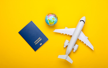 Tourism and travel concept. Emigration. Globe,  passport and passenger plane figurine on yellow...