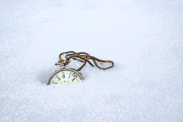 Antique rotten pocket watch, partially buried in snow