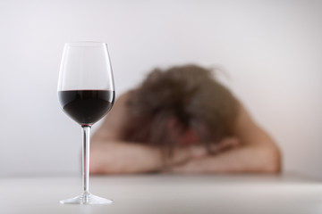 Glass with wine/ alcohol on blurred view of a lonely and desperate drunk man