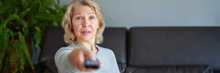 Mature senior woman watching television at home