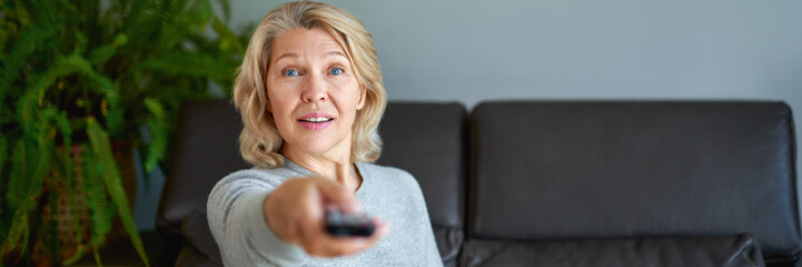 Mature senior woman watching television at home