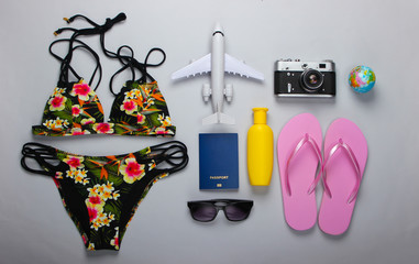 The concept of a beach holiday. Sea resort. Summer background. Bathing suit, travel accessories on gray background. Top view. Flat lay