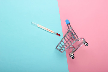 Shopping trolley with a thermometer on a blue-pink pastel background. Hot discounts. Supermarket....