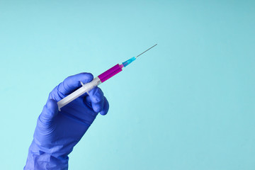 Medic's hand in latex gloves holds syringe with a vaccine. Vaccination