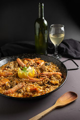 Seafood paella in rustic setting, cloudy wine
