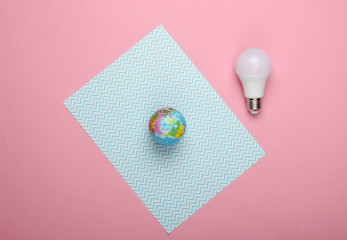 Save the planet. Eco concept. Energy-saving led light bulb and globe on pink-blue pastel background