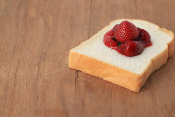 Sliced white bread with jam on wooden background. 