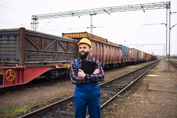 Railroad freight transportation. Shipping worker looking at train coming to the station. Organizing...