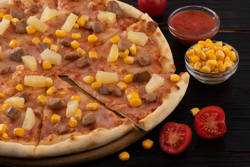 Pizza with chicken, pineapple and corn isolated on wood background