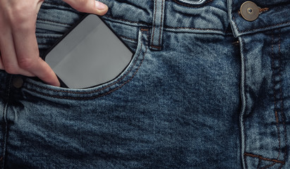 Hand pulls smartphone out of front jeans pocket