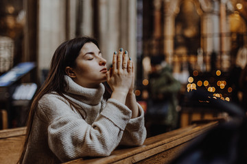a woman praying on her knees in an ancient Catholic temple to God. copy space