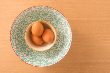 Huevos dentro de un bol con patrones de colores sobre una tabla de madera con espacio, pascua