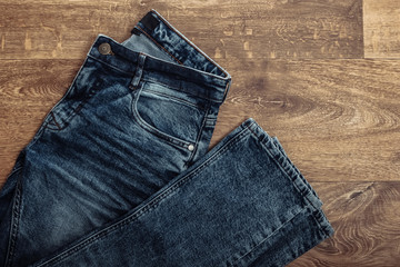 Stylish jeans on a wooden floor. Top view