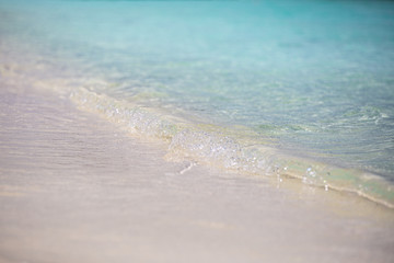 Turquoise waves lap over the fine sands on a tropical beach. Beach details, calmness and relaxation background
