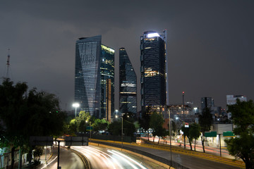 Fototapeta na wymiar Edificios de la ciudad de México en un día lluvioso y una avenida en la parte inferior con un barrido de luces de carros