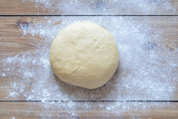 Fototapeta na wymiar bread dough ready for kneading. preparing the dough on a wooden table. Knead dough in homemade kitchen