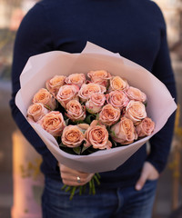 Young man with a gift bouquet of fine peach roses, mono bouquet of roses. Peony roses flowers....