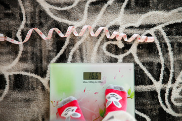 meter in front of the scale, the girl stands with her feet on the scale indoors.-Overweight - 342849203