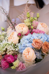 Young woman holding delicate flower bouquet. Bouquet of fresh beautiful flowers wrapped in pink paper. Mother`s day.