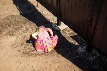 little girl are playing  with a cat under the fence,  are expecting a miracle