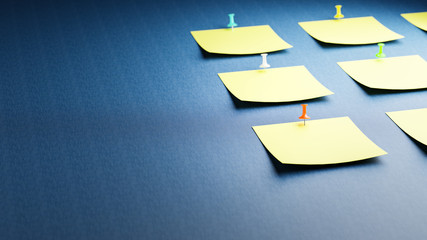 Empty adhesive notes attached to a blue fabric bulletin board. Differently colored thumbtacks /...