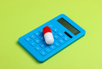Calculation of the cost of medical expenses. Calculator and pill on green background.