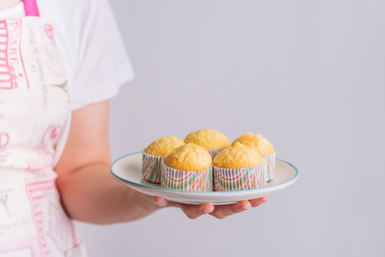 chica sosteniendo en su mano un plato con magdalenas caseras, espacio de copia