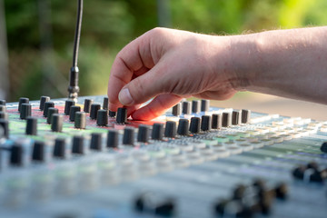 Closeup of a sound engineer at mixing desk at open air - might be a wedding or a concert