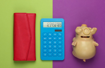 Manage family budget. Shopping costs. Blue calculator with red leather wallet and piggy bank on...