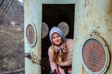 Young woman looks out of the vintage cable car cabin in Chiatura.