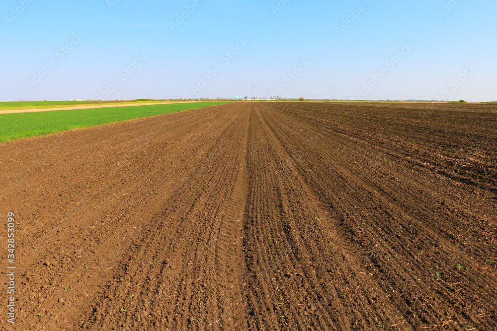 Sticker plowed field in spring time with blue sky