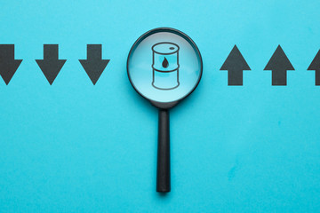 Oil rise and fall concept with magnifying glass, icons on wooden blocks.