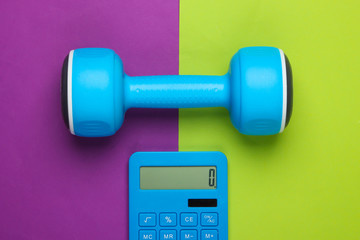 Fitness, weight loss still life. Calorie Counting. Calculator and dumbbell on green purple background. Minimalism. Flat lay