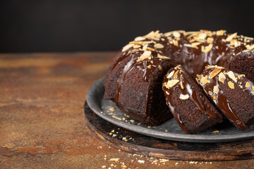 Sweet Homemade Dark Chocolate Bundt Cake with almonds over dark background, copy space. Selective...