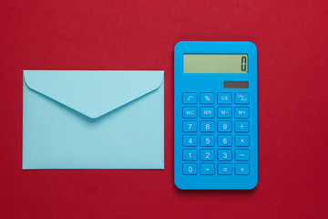 Calculator with envelope on red background. Top view