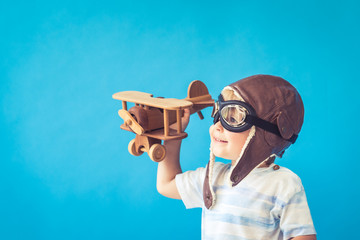 Happy child playing with toy wooden airplane