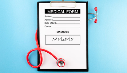 Malaria - diagnosis in medical form. Stethoscope (red) and blank clipboard with a sheet of white...