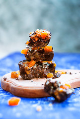 Sliced ​​homemade chocolate with dried apricots, raisins, flax seeds, sesame seeds. on a blue background.